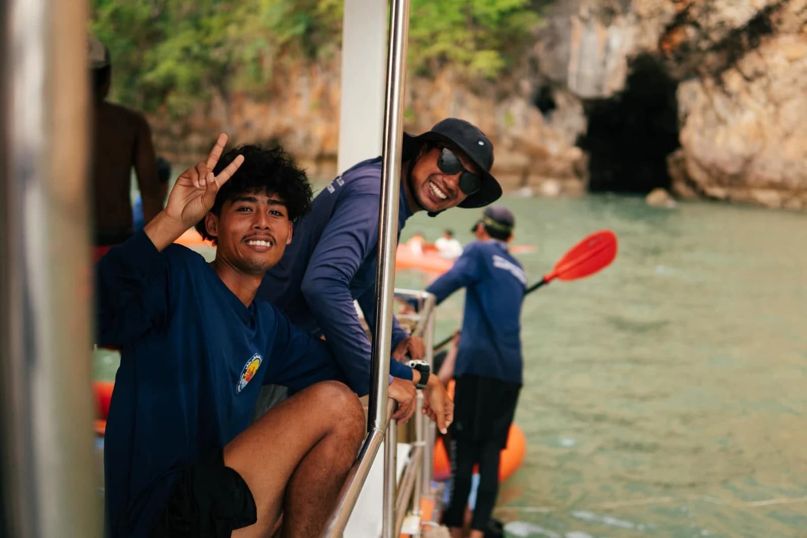 Crew member beside the boat access area with paddlers on the water behind
