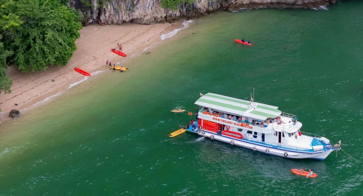 Tour boat and red canoes beside a small beach backed by cliffs