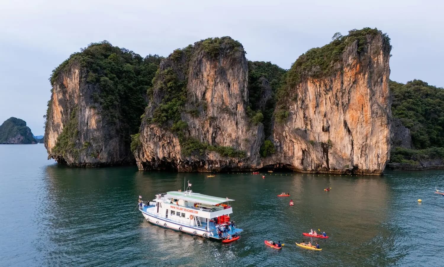 Tour boat and guided canoes beside steep limestone islands